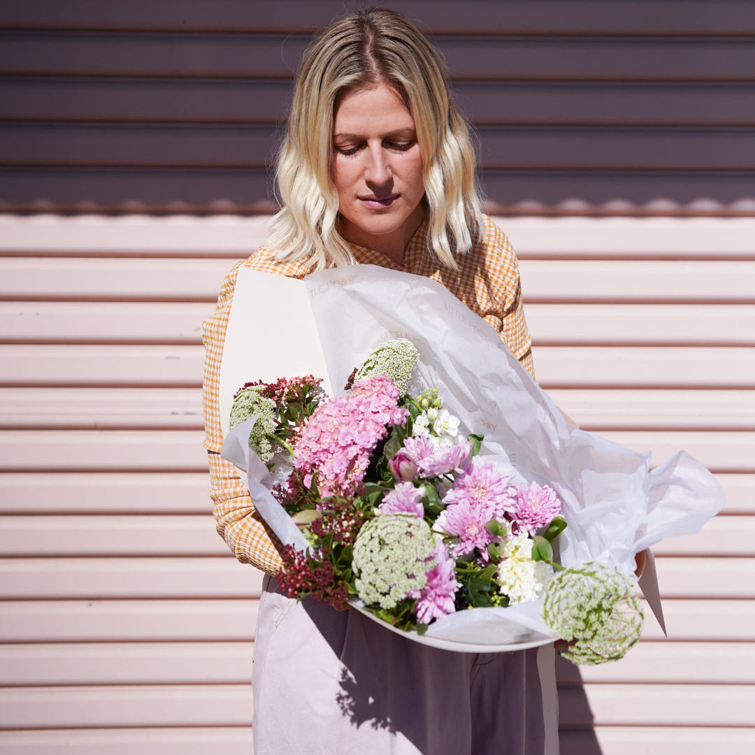 Woman holding a bouquet of flowers against a corrugated metal background