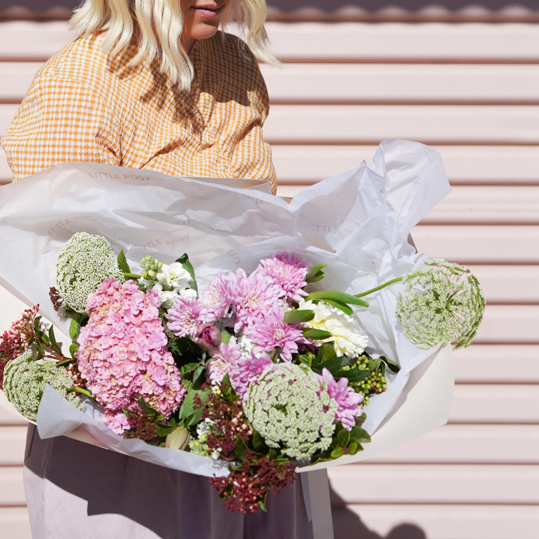 Person holding a bouquet of flowers against a pink background